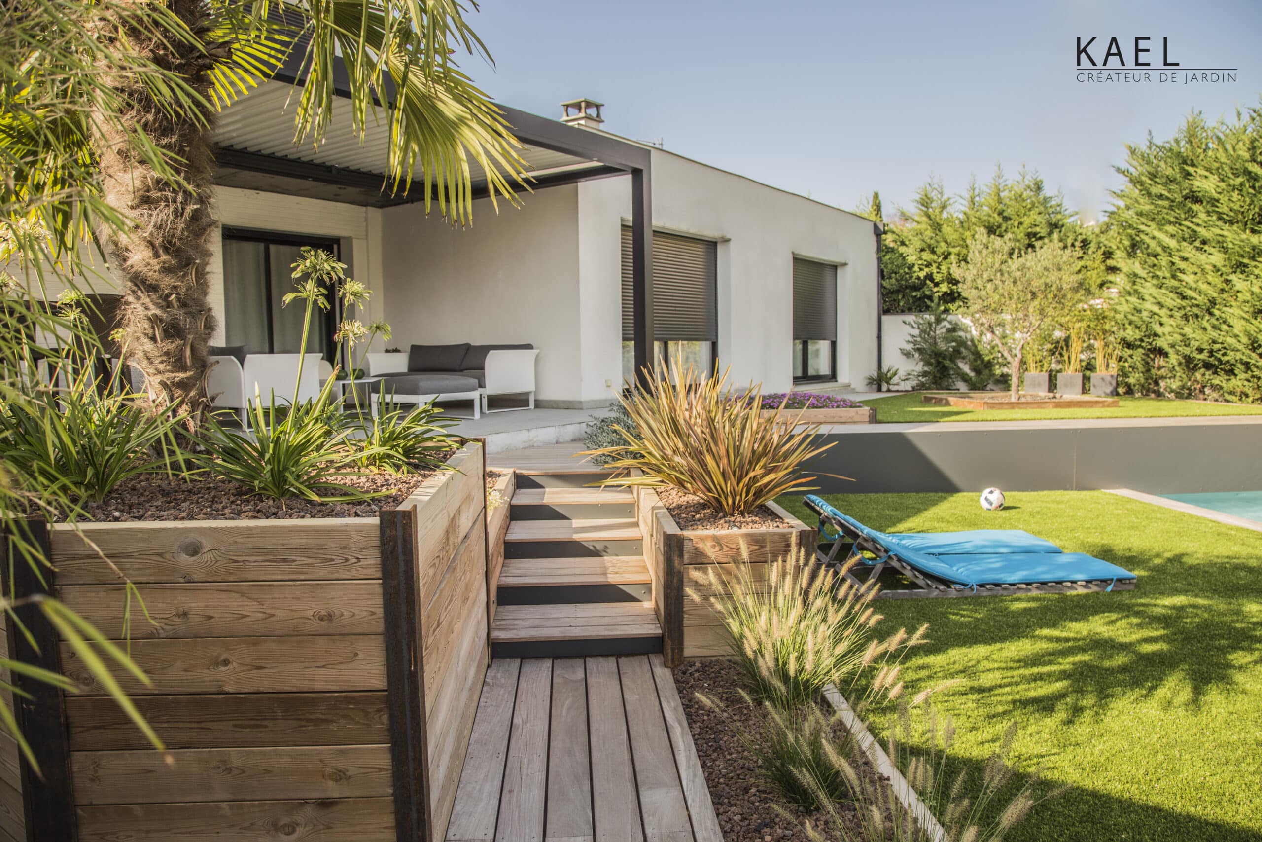 Jardin design KAEL Créateur de Jardin : terrasse bois, pergola, piscine et mobilier extérieur dans un cadre moderne.