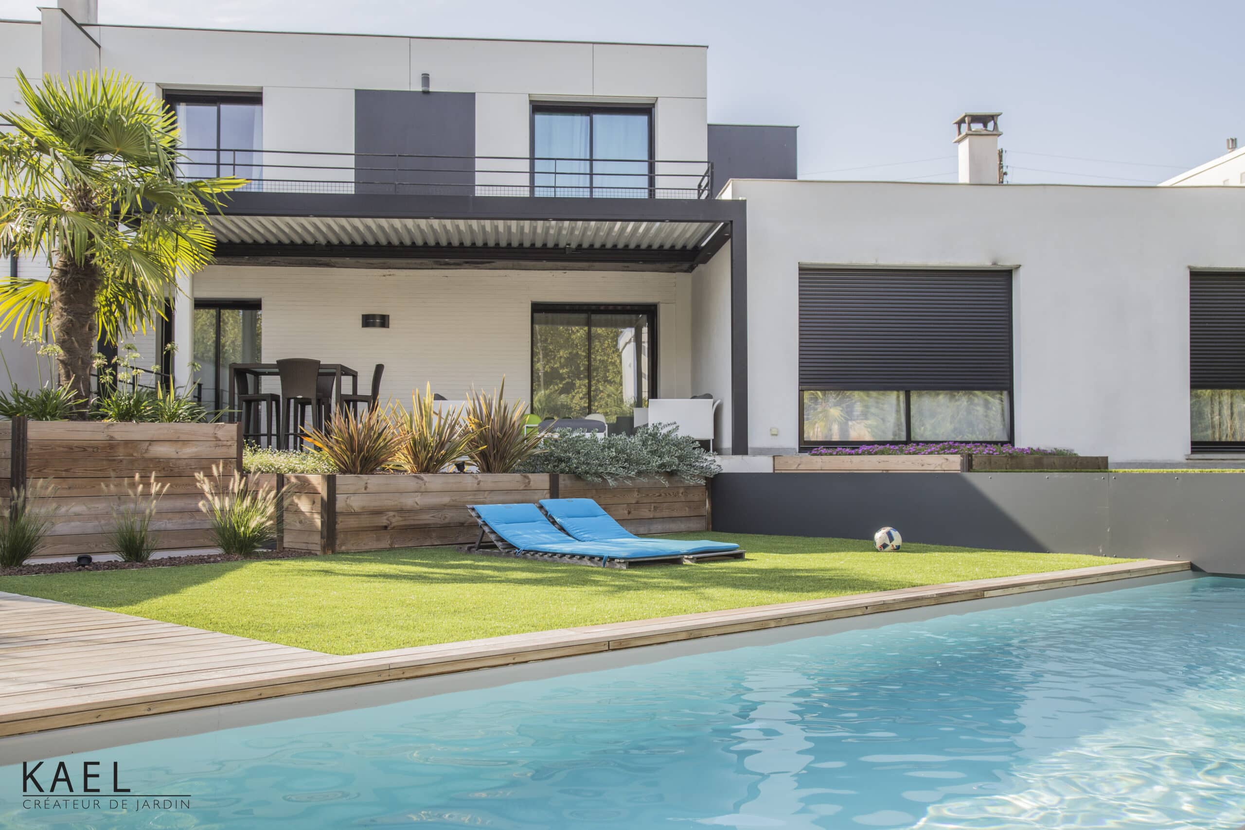 Villa moderne avec piscine, jardin paysager, transats bleus et terrasse par KAEL Créateur de Jardin.
