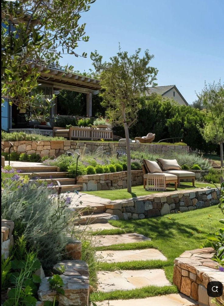 Jardin en restanques avec murs en pierre sèche, mobilier d'extérieur et végétation méditerranéenne luxuriante.