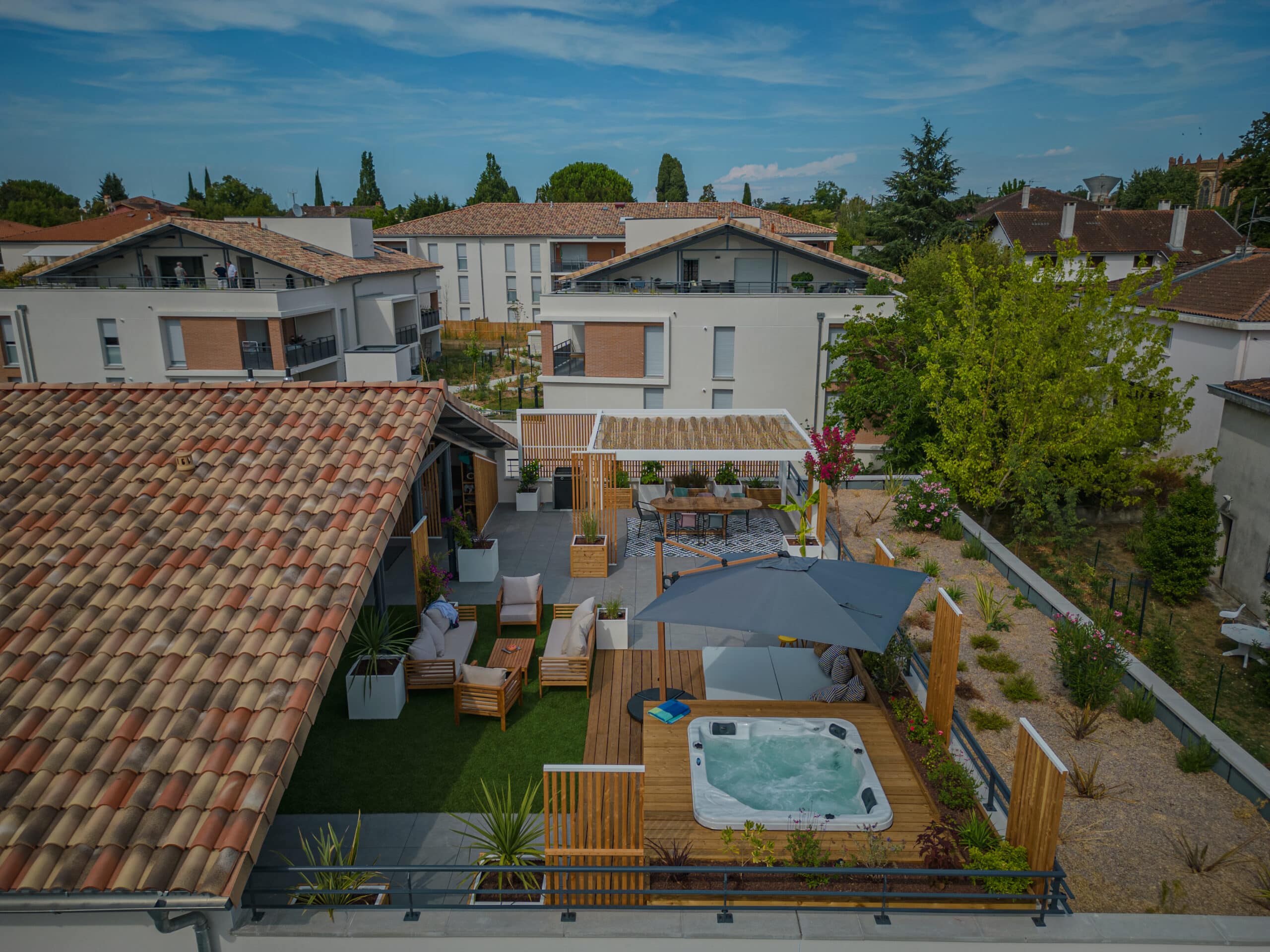 Terrasse sur toit avec spa, salon de jardin et pergola bois dans un quartier résidentiel moderne.