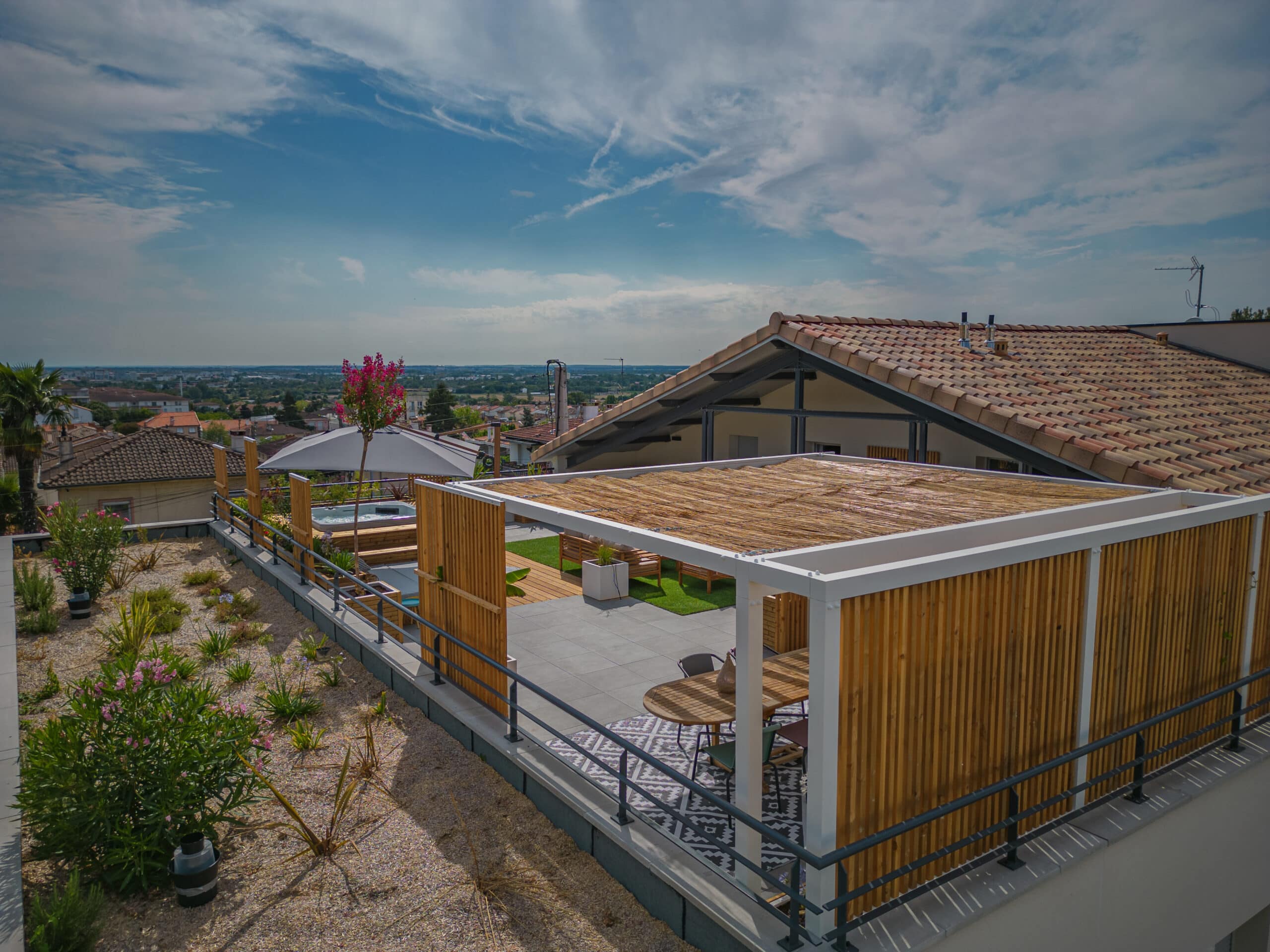 Terrasse de toit moderne avec pergola en bois, salon de jardin et vue panoramique sur la ville sous un ciel nuageux.